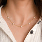 Dainty opal necklace with tiny opal flower charms worn on female model