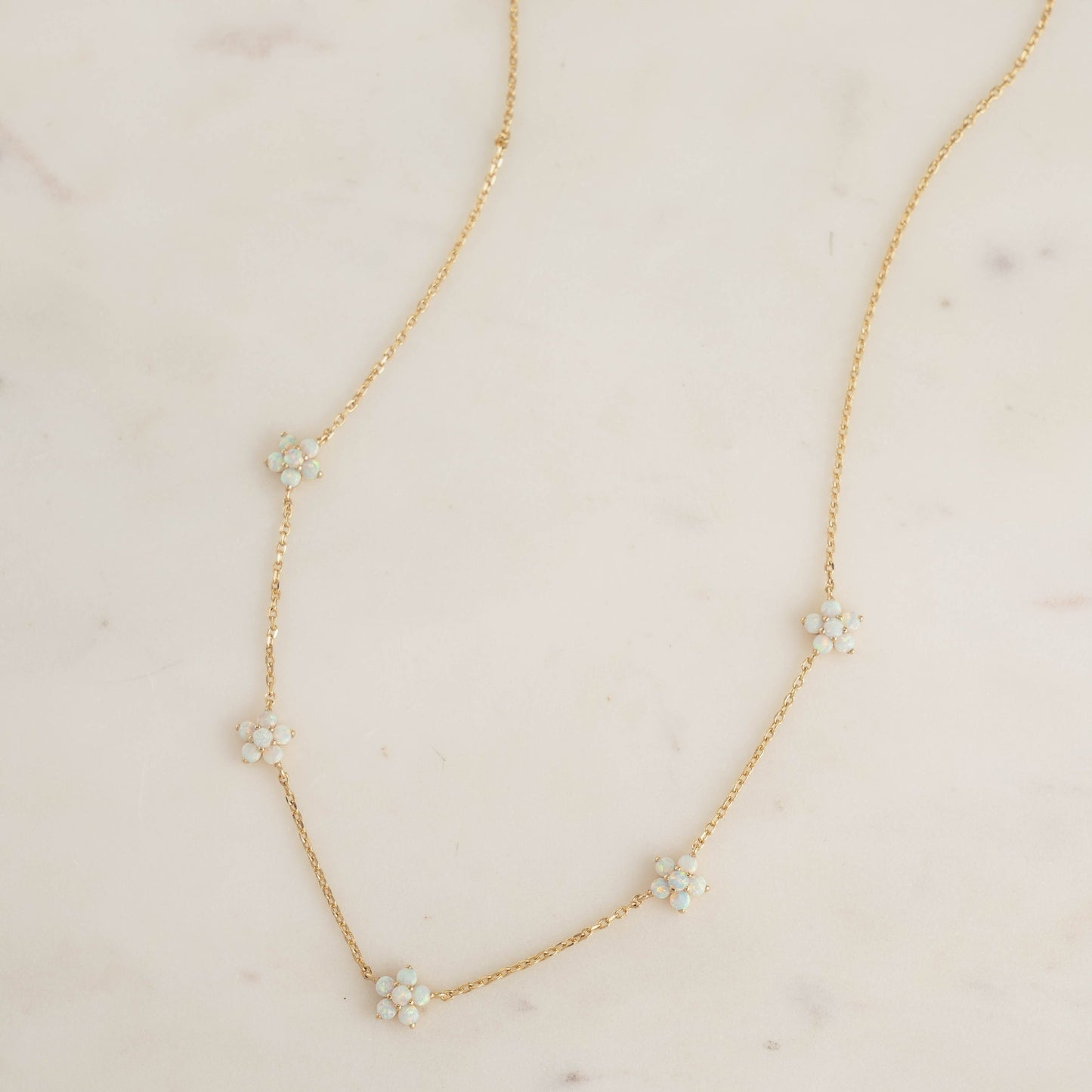 Delicate opal charm necklace plated in 14k gold on white background