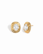 Gold oval bezel statement stud earrings with clear cubic zirconia, shown from the front and side on white.
