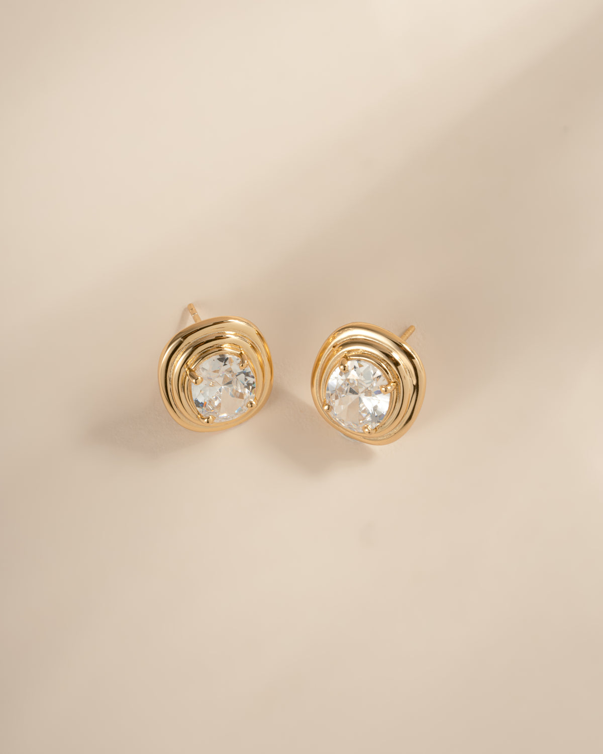 Angled view of gold oval bezel statement studs with their posts visible.