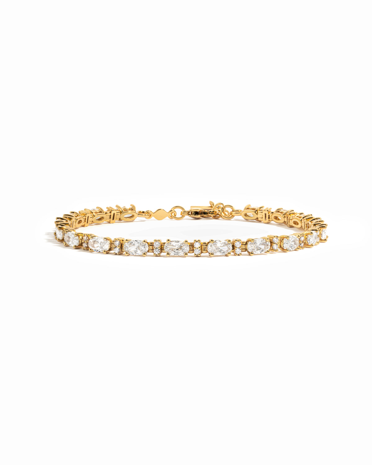 A gold tennis bracelet featuring white oval and round diamonds.
