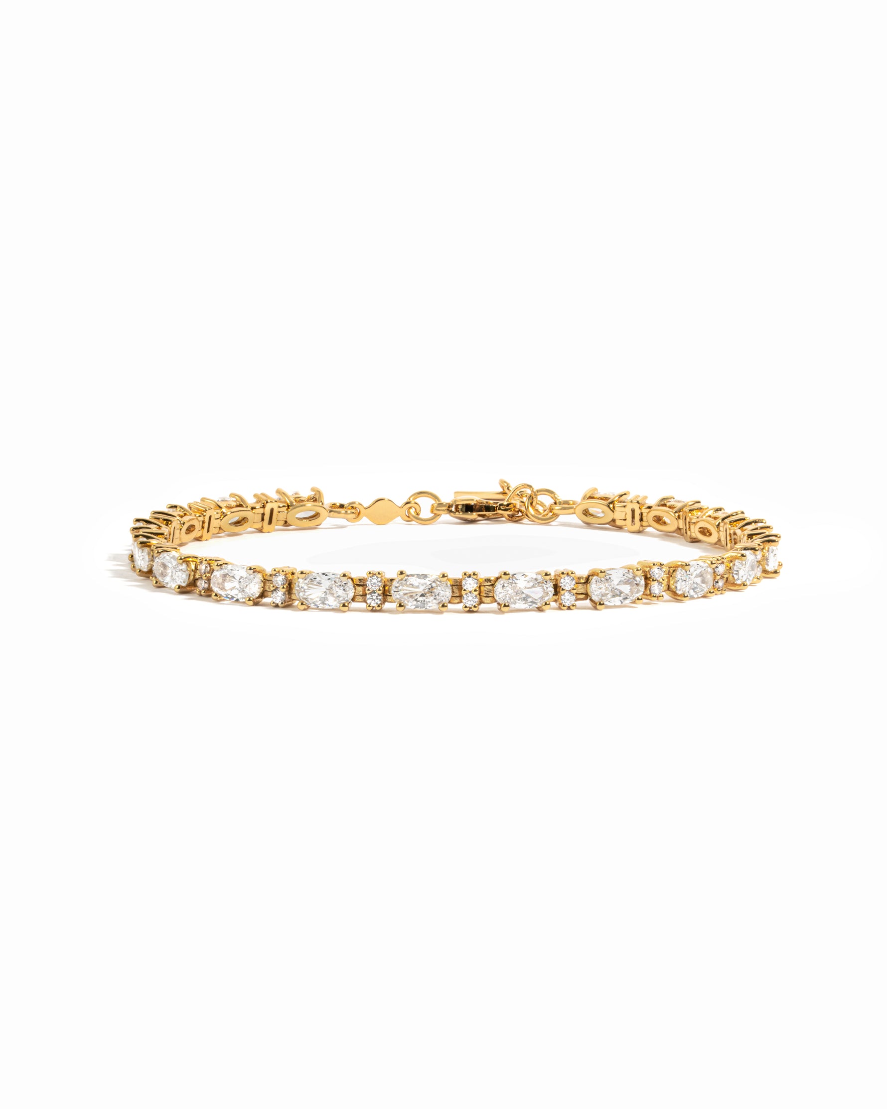 A gold tennis bracelet featuring white oval and round diamonds.