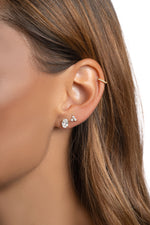Close view of a model's ear wearing a 6x8mm oval stud beside a smaller stud.