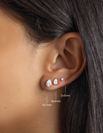 gold cubic zirconia stud earrings in various sizes, pear stud earring in 5x7mm, followed by a 4x6mm pear stud earring, and lastly, a 2x3mm pear stud earring on womens ear 