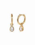 Pair of gold plated huggie earrings with removable pear-cut clear cubic zirconia charms on a white background.