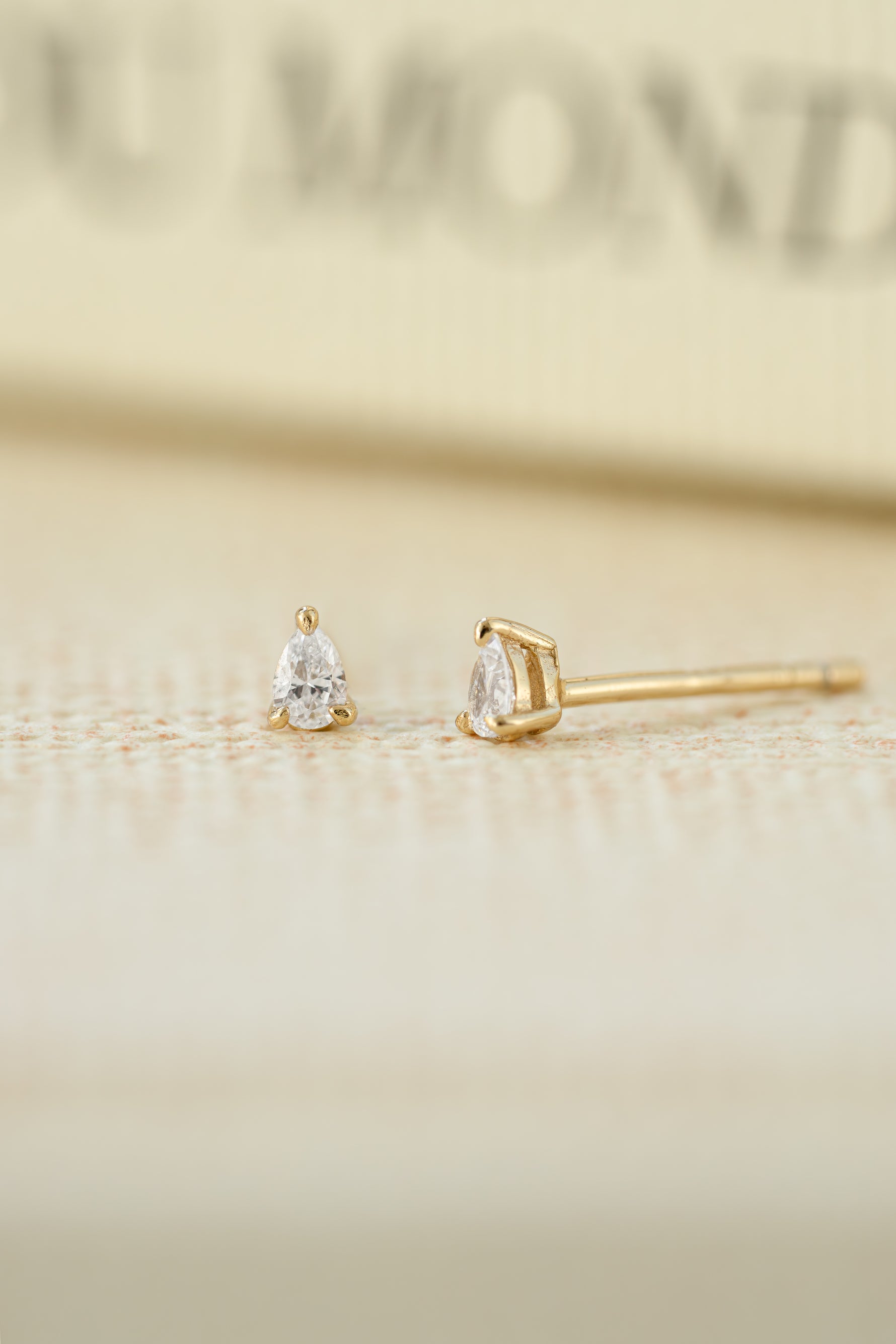 gold 2x3mm pear stud earring on neutral background