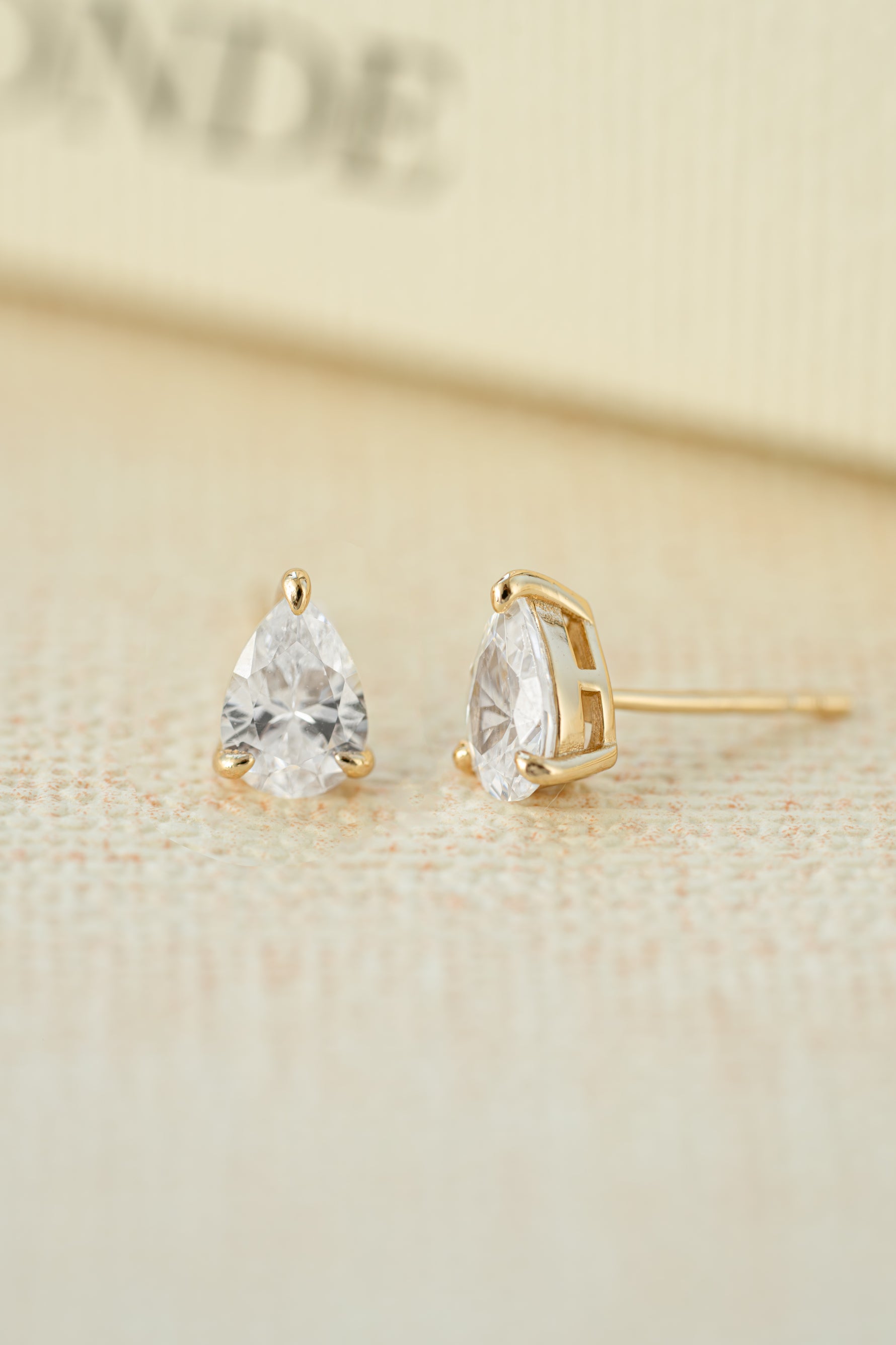 gold 5x7mm diamond pear stud earring neutral background 