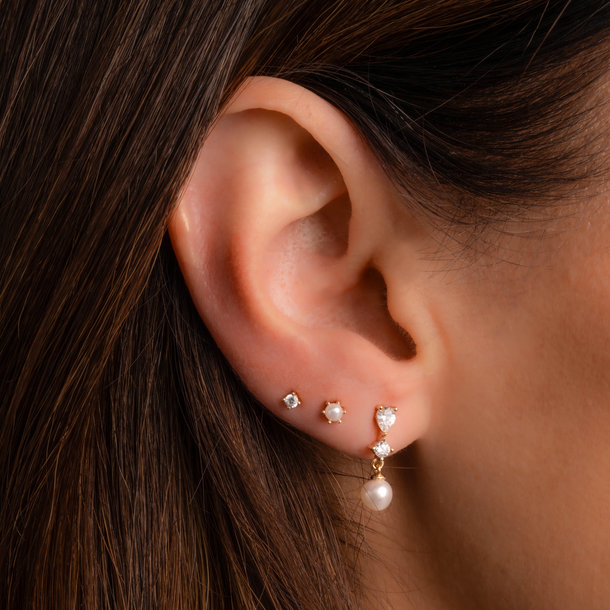 Model wearing Pearl Drop Earrings in gold with other dainty pearl stud earrings