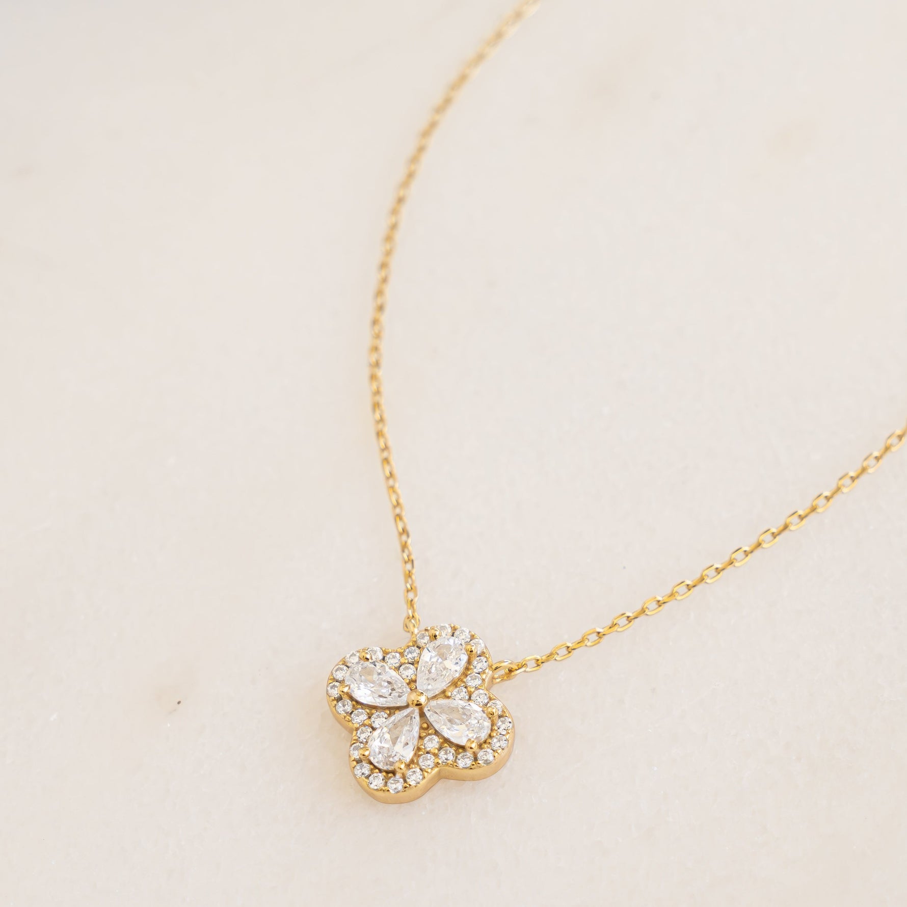 close up of delicate diamond pendant necklace of a four leaf clover made with pear shaped stones in the shape of a four leaf clover