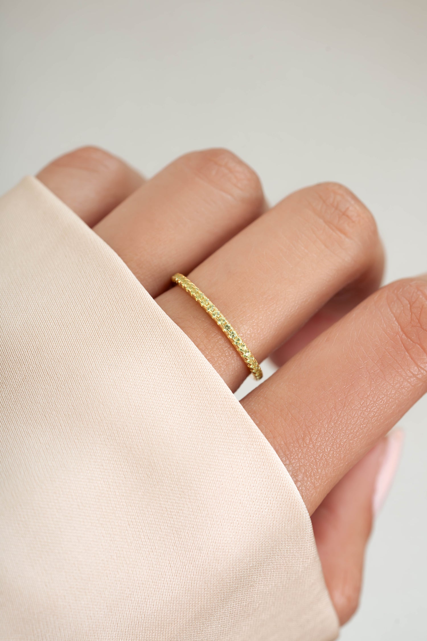 gold peridot birthstone eternity ring on womens hand