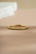 gold peridot birthstone eternity ring neutral background