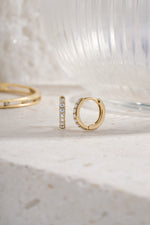 gold plated 10mm diamond studded huggie hoop earring neutral background