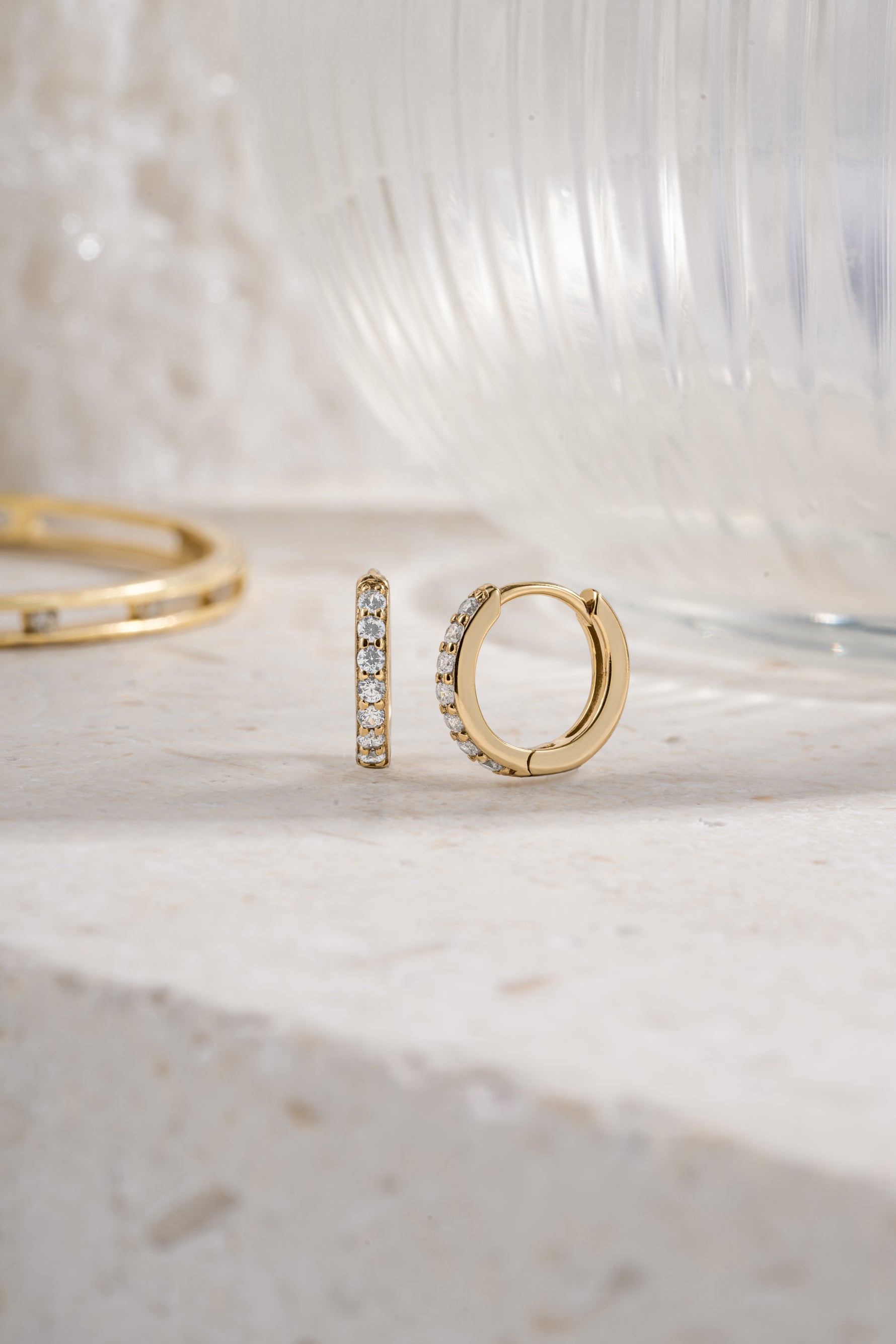 gold plated 10mm diamond studded huggie hoop earring neutral background