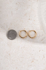 gold 11mm minimalist hoop earring being compared to size of dime neutral background