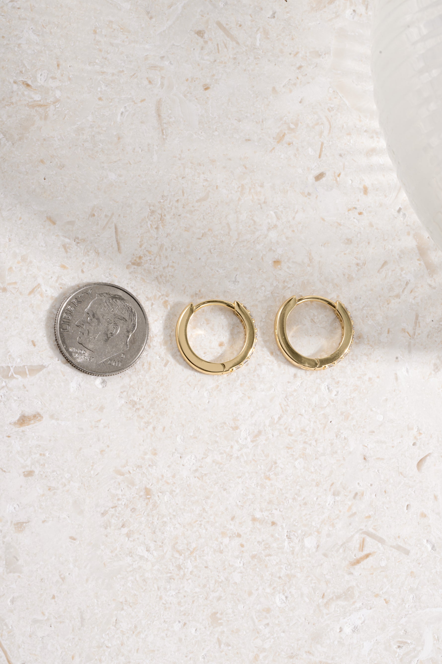 gold plated 11mm studded huggie being compared to a dime size