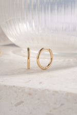 gold 13mm minimalist hoop earrings on a neutral background 