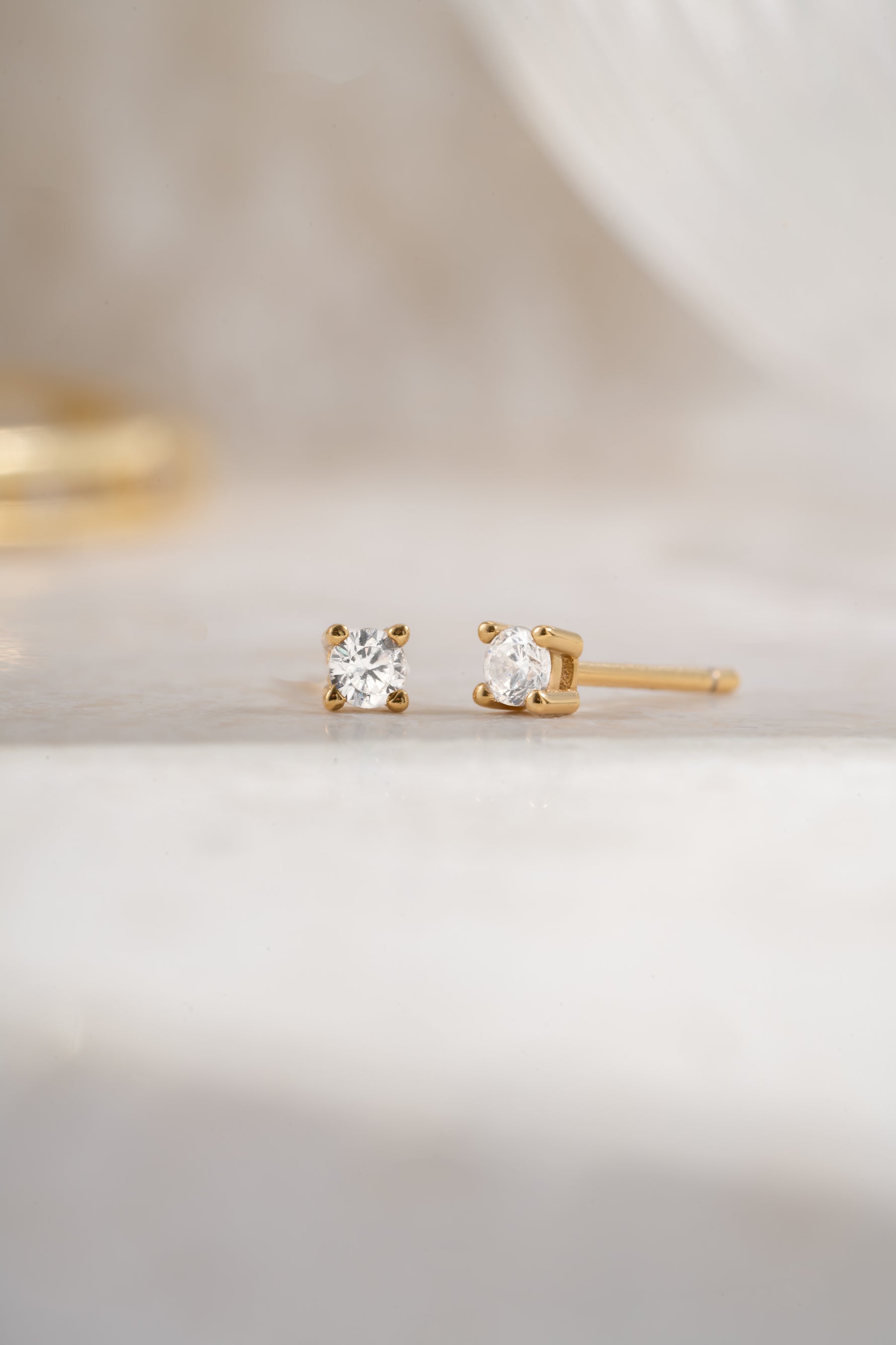 Gold plated 2.5mm diamond solitaire stud earrings angled view on white background