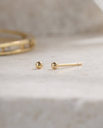gold 2mm ball stud earring neutral background