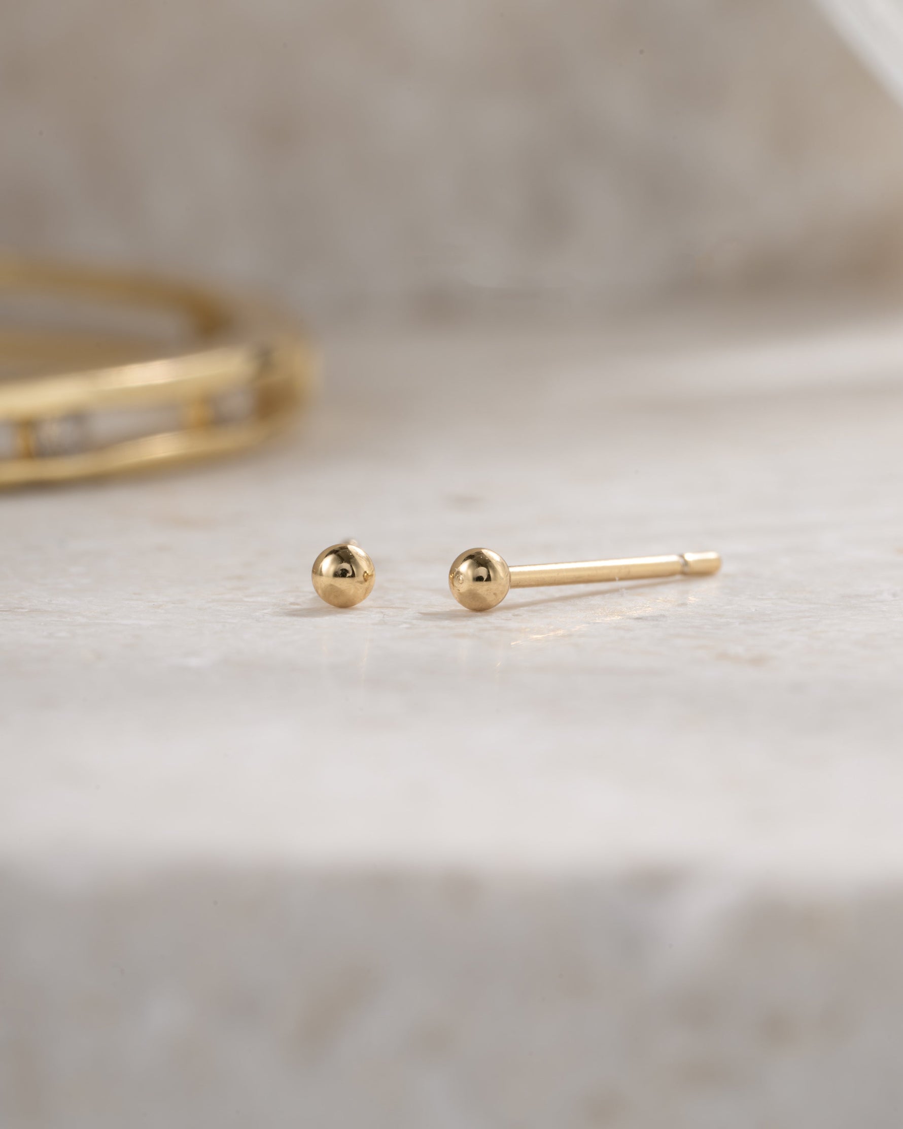 gold 2mm ball stud earring neutral background