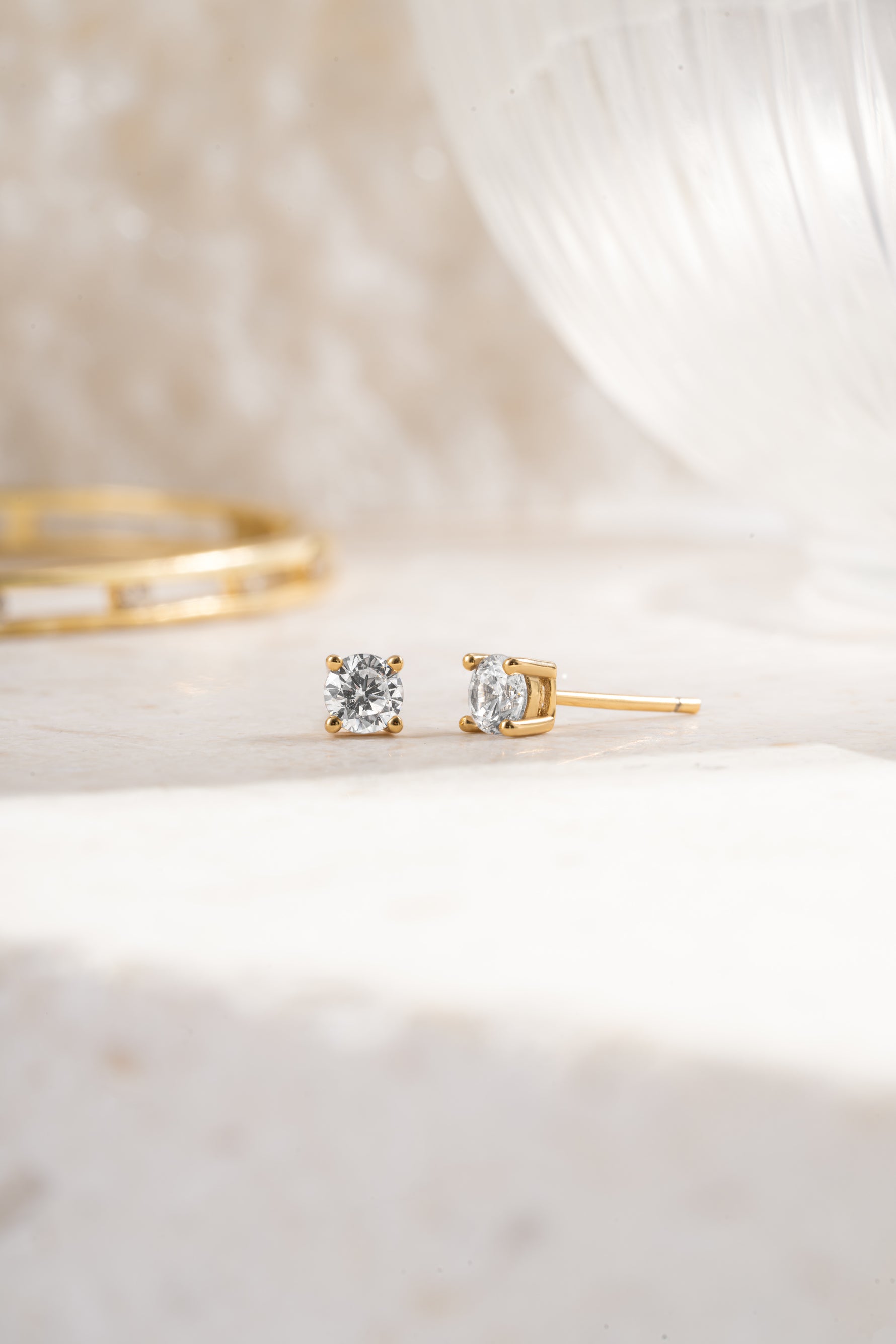 gold plated 4mm solitaire studs angled view neutral background