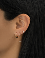 Gold plated 7mm studded huggie earrings on womens ear with minimalist ear stack
