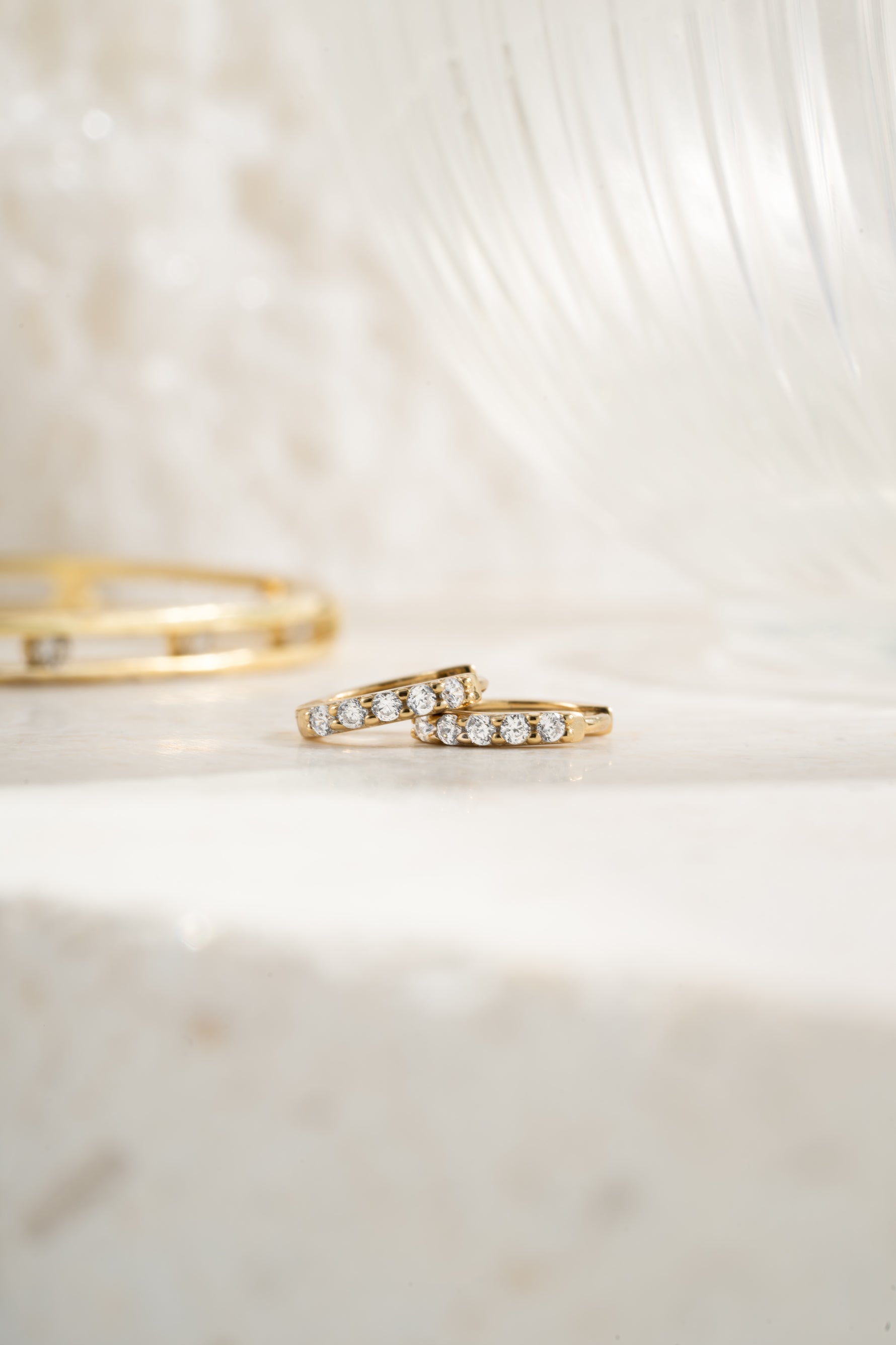 Gold plated 7mm studded huggie earrings with cubic zirconia stone neutral background