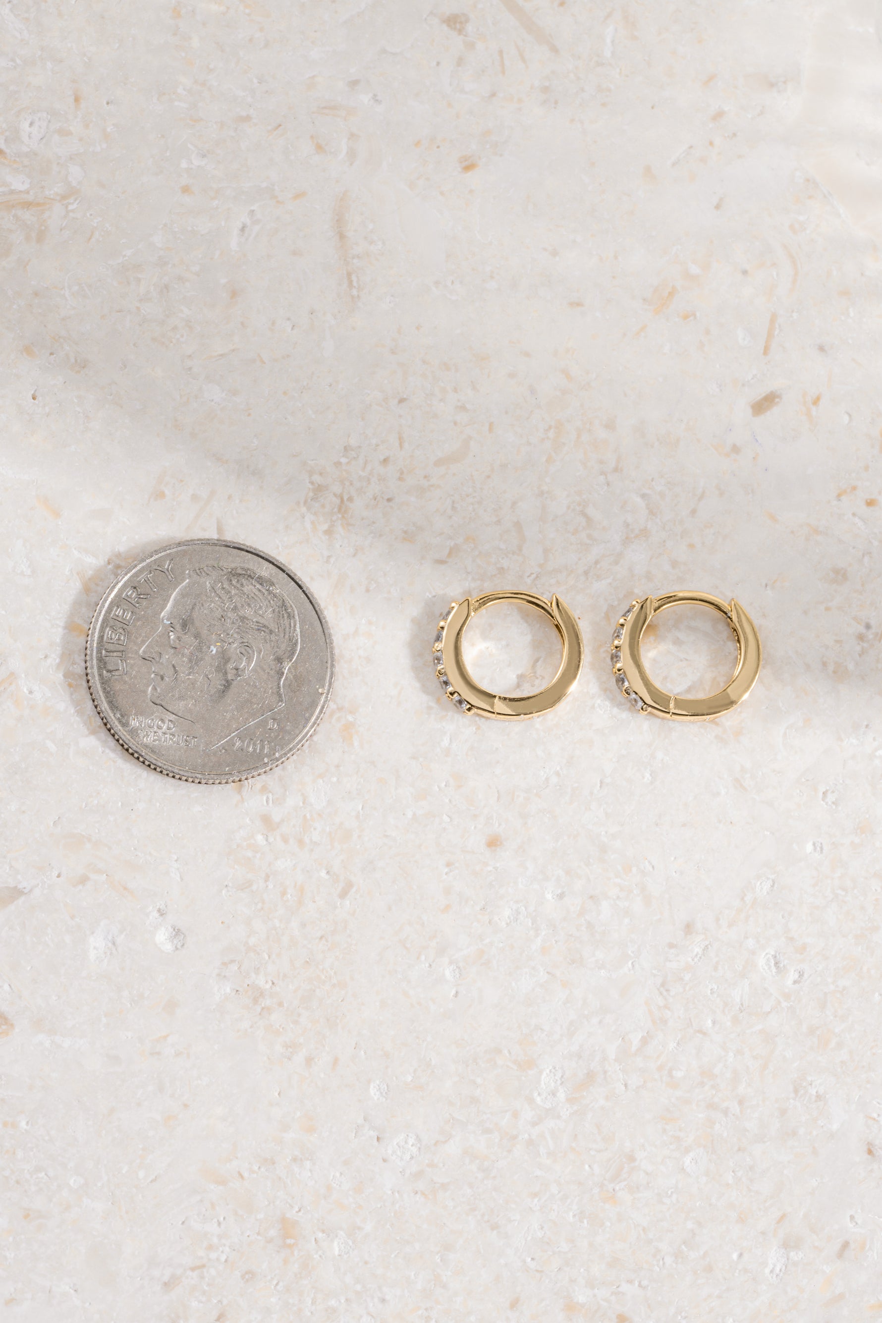 Gold plated 7mm studded huggie earrings compared to size of dime