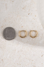 8mm gold hoop earring being compare to size of dime on neutral background