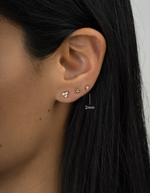 Closeup gold plated diamond solitaire stud earring layered on womens ear 