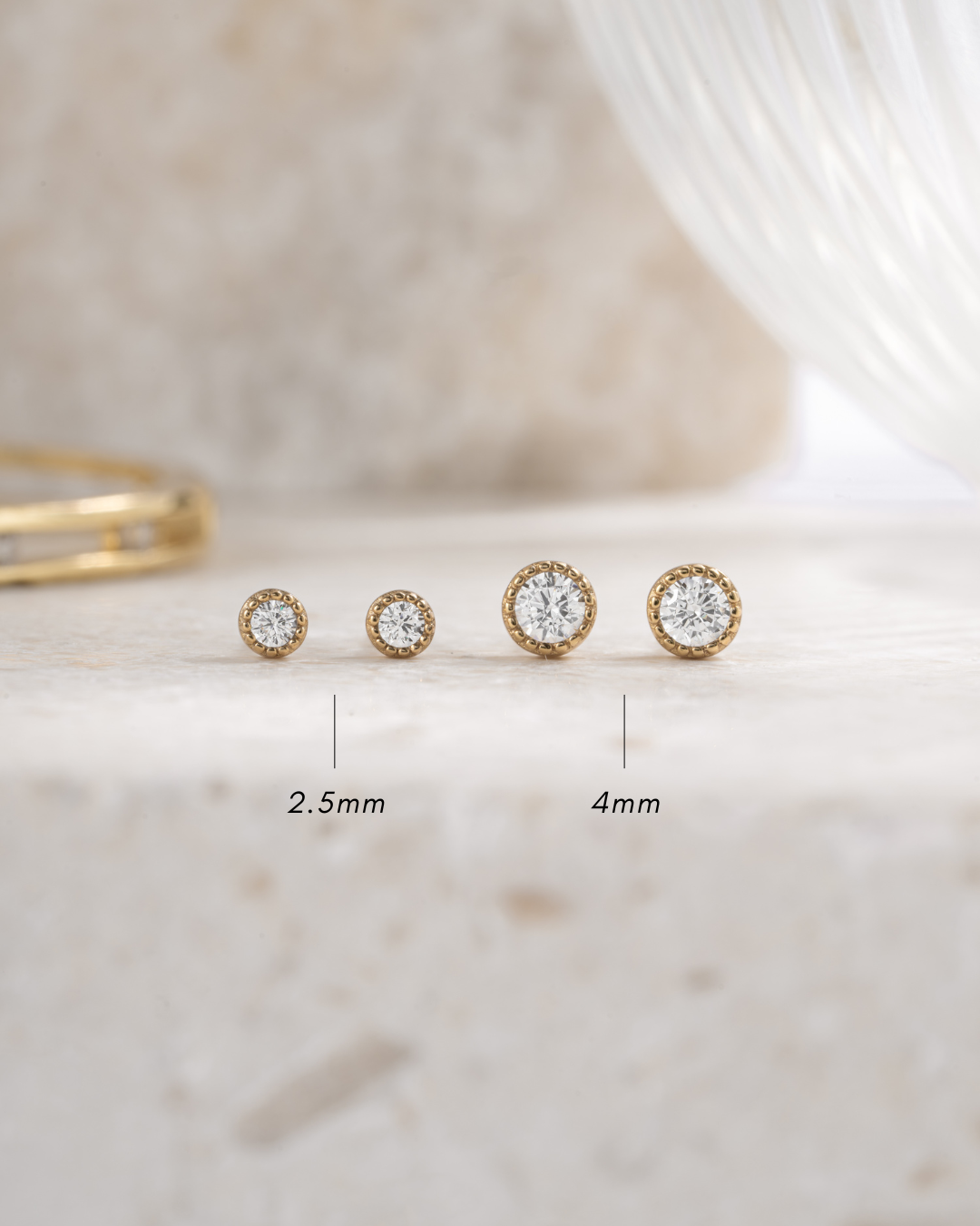 gold 4mm diamond stud earrings and gold 2.5mm diamond stud earrings neutral background front view