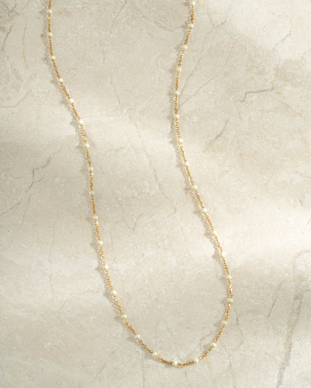gold cream enamel beaded necklace neutral background