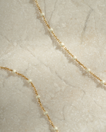 gold cream enamel beaded necklace close up neutral background