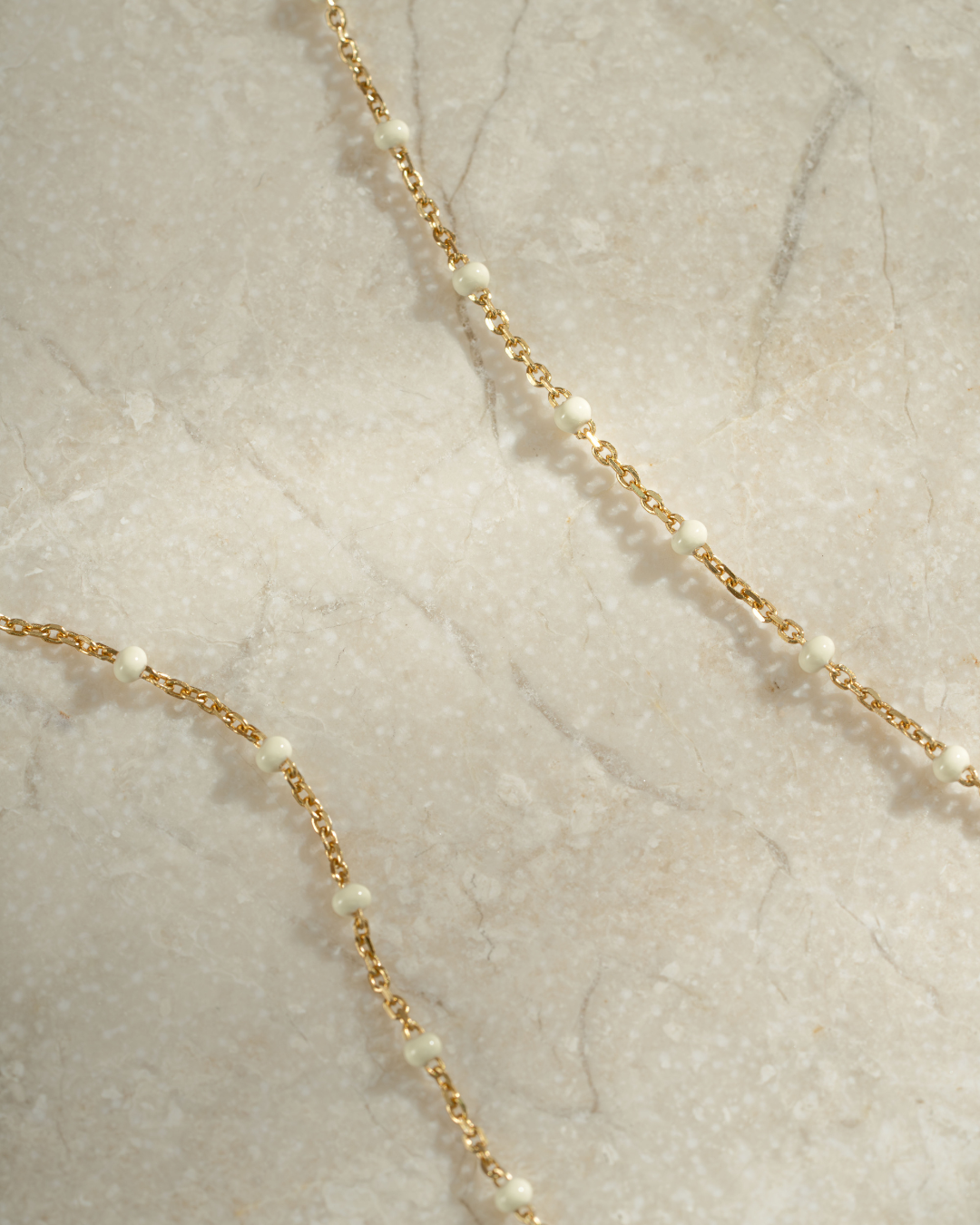 gold cream enamel beaded necklace close up neutral background