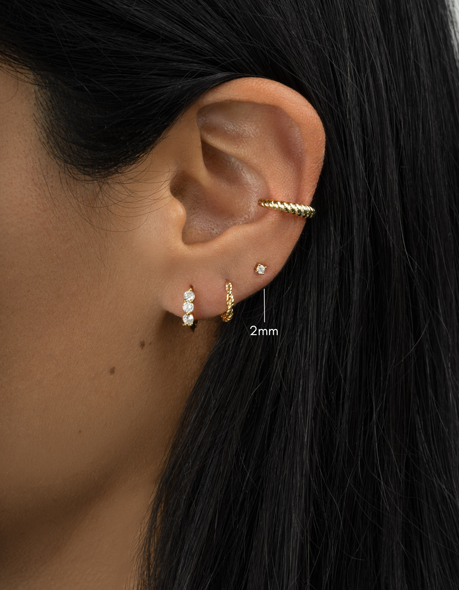 Gold plated earring stack with 2mm solitaire stud earrings on womens ear