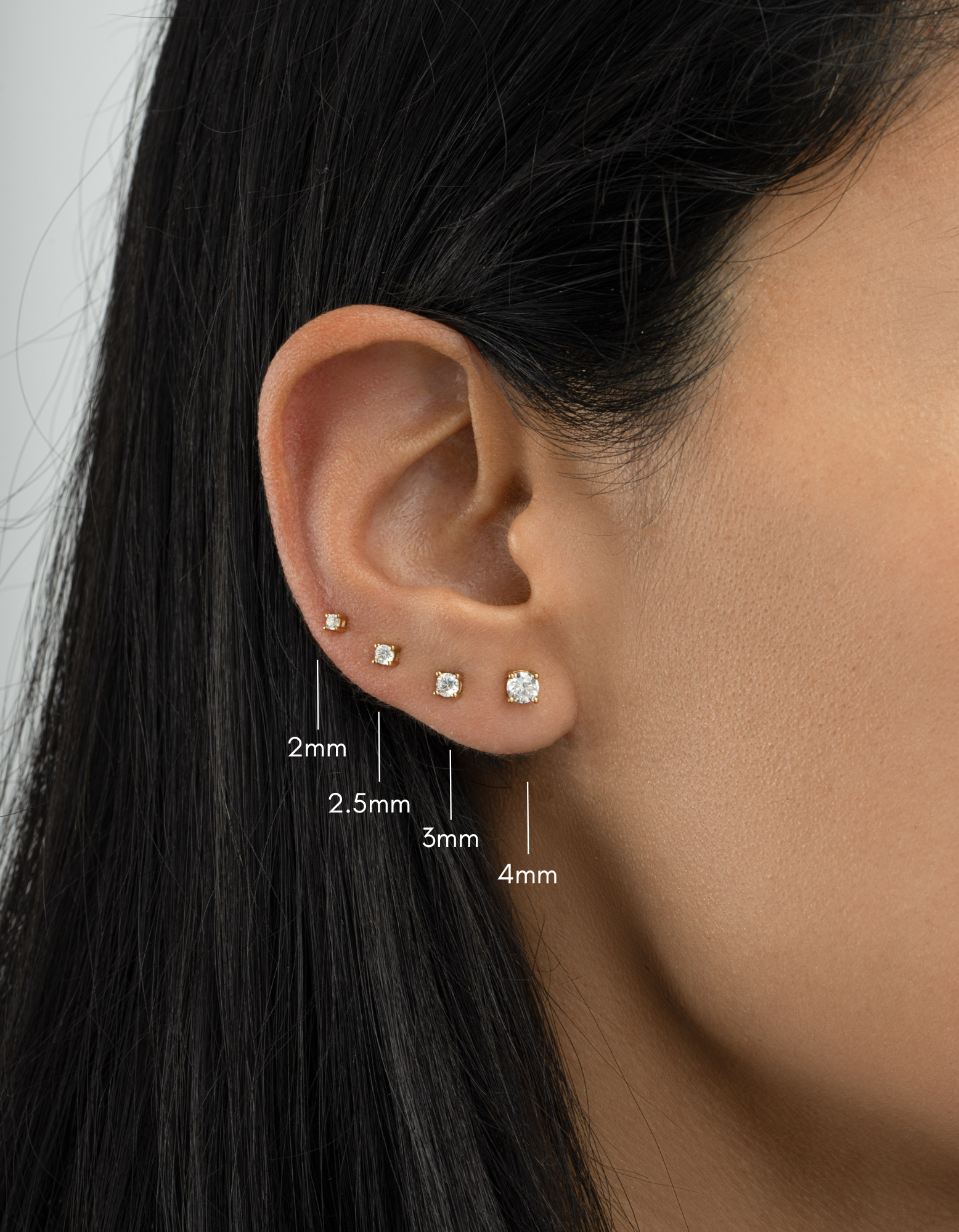 Gold plated diamond solitaire stud earrings on womens ear in sizes ranging from 2mm, 2,5mm, 3mm and 4mm 