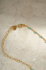 Close-up detail of clasp on gold turquoise enamel beaded necklace neutral background
