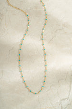 gold turquoise enamel beaded necklace neutral background