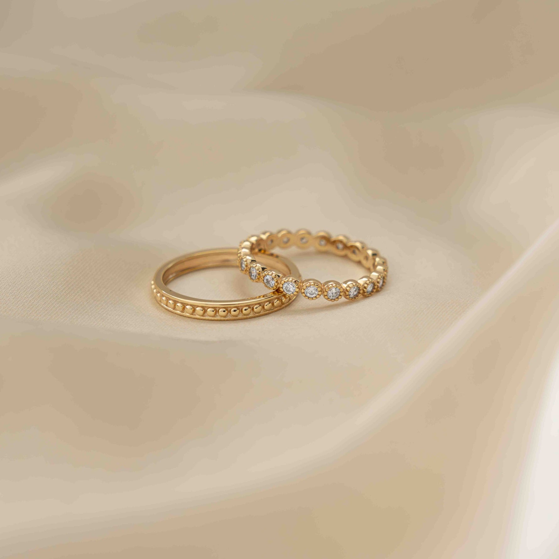 Tiny gold ring set with cz diamonds plated in 14k gold, showcased on tan silk