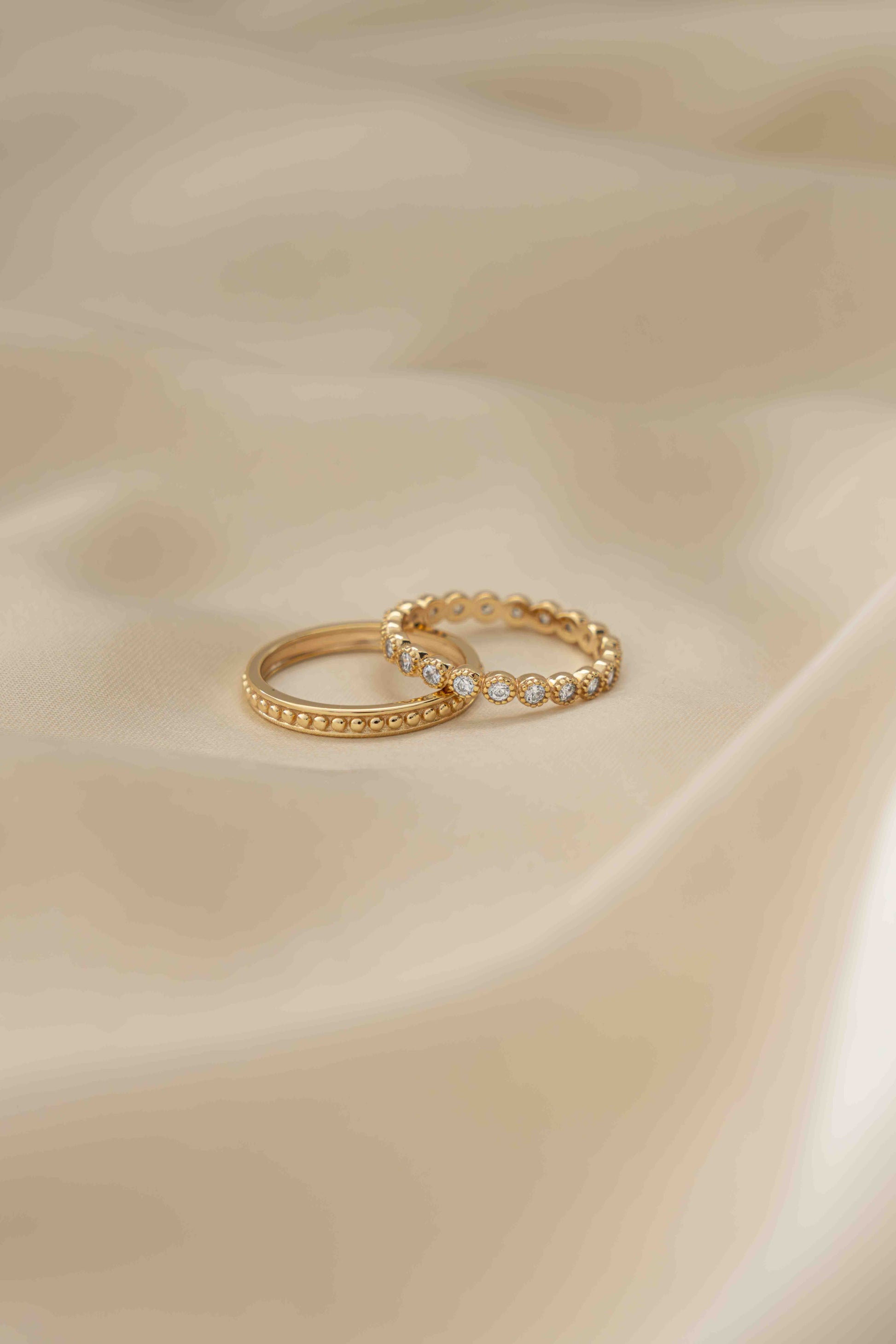 Tiny gold ring set with cz diamonds plated in 14k gold, showcased on tan silk