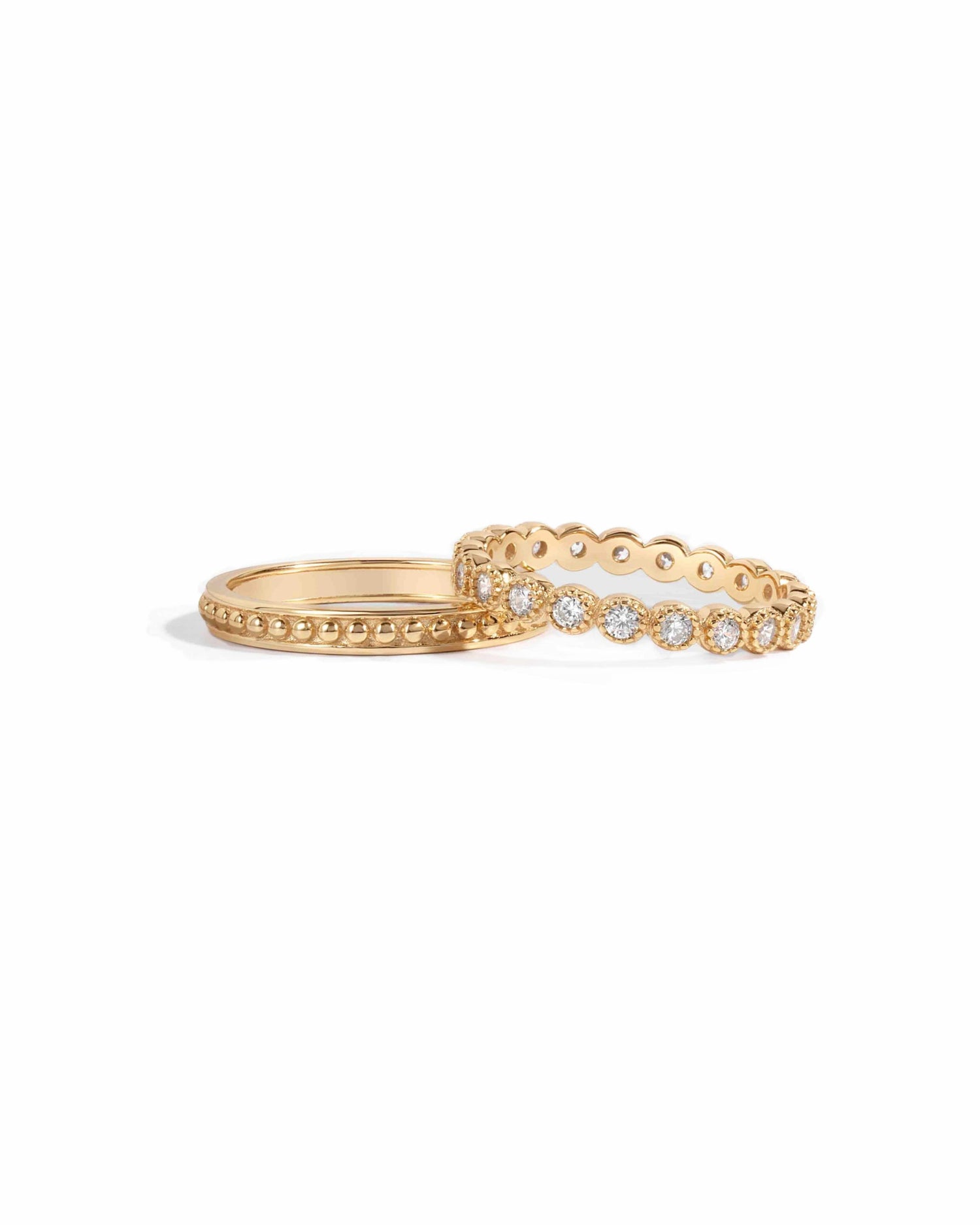 two gold rings, one studded with cubic zirconia diamonds, and one with a plain beaded design