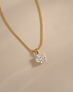 Close-up of the gold round CZ pendant showing its four-prong setting.