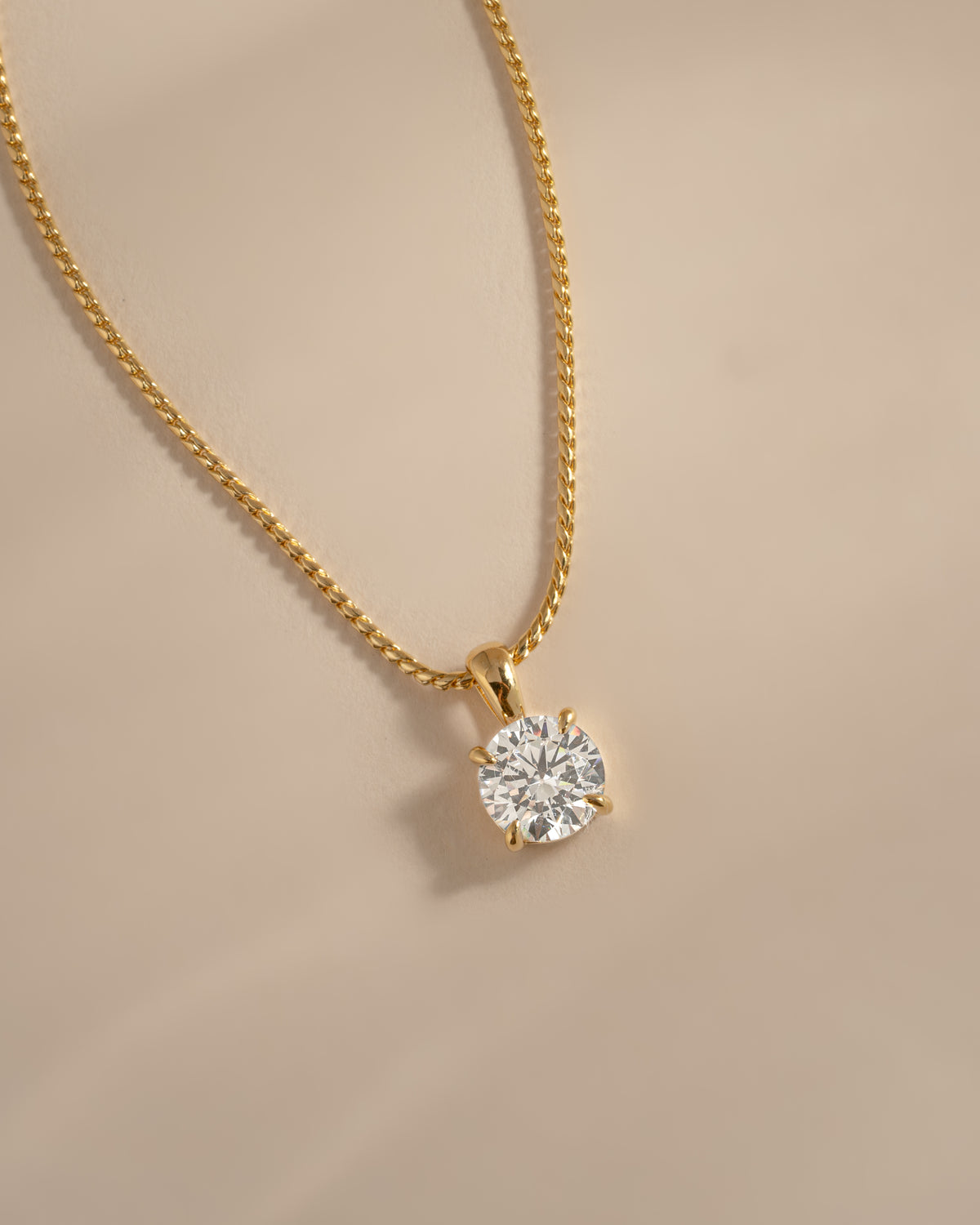 Close-up of the gold round CZ pendant showing its four-prong setting.