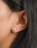 gold round solitaire stud diamond earring on womens ear 