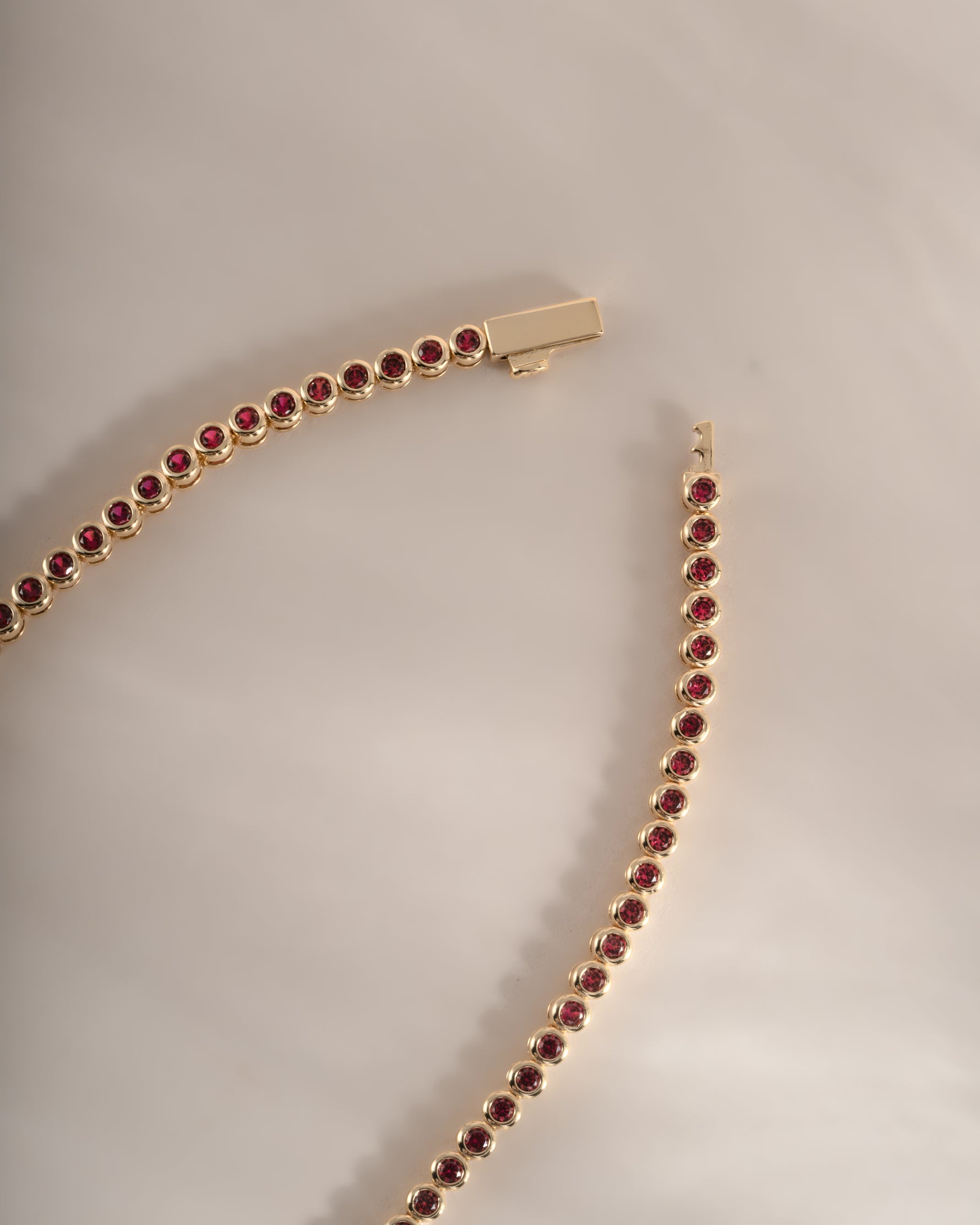 Gold Ruby Bezel Tennis Necklace by Sami Jewels with dainty design and box clasp, featuring sparkling rubies along a sleek gold chain.