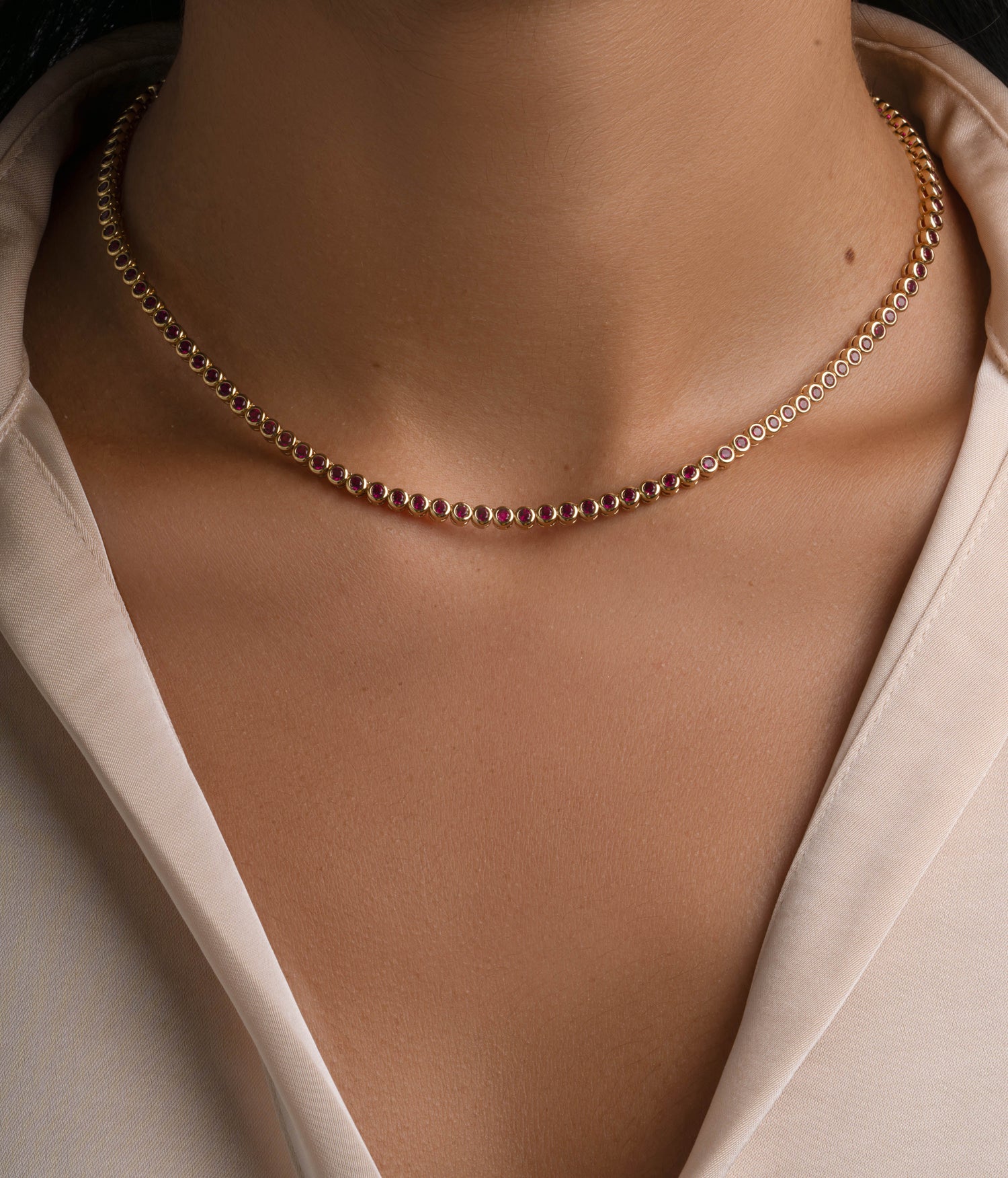 Gold Ruby Bezel Tennis Necklace by Sami Jewels displayed on a model, featuring a sleek design with vibrant ruby stones.
