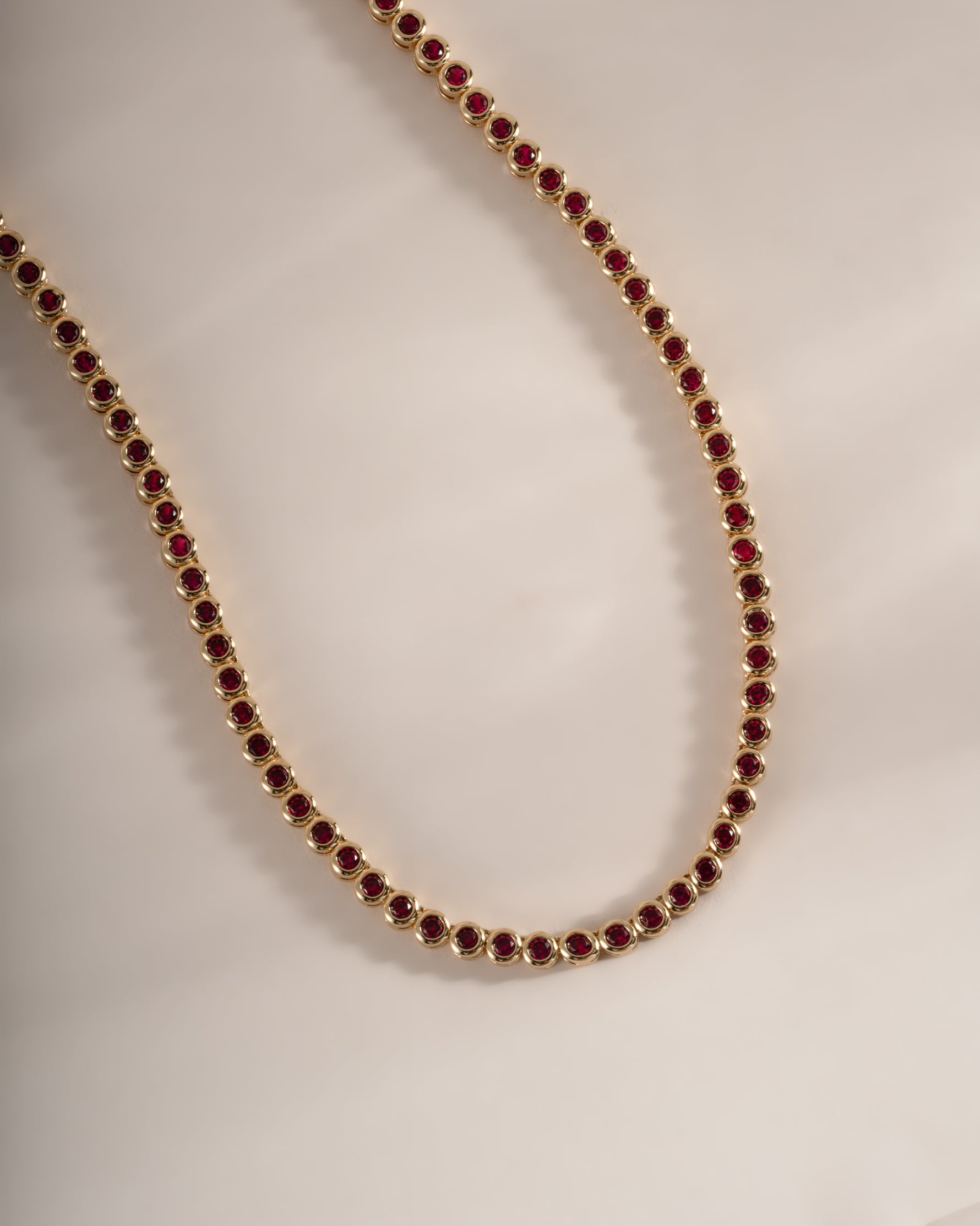 Gold Ruby Bezel Tennis Necklace by Sami Jewels featuring a row of sparkling rubies set in a sleek gold bezel design.
