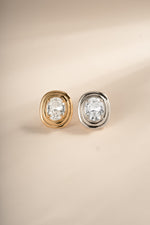 Gold and silver oval bezel statement studs shown side by side.