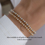 Model wearing stackable bracelets in  two tone tennis chain style.