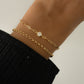 Minimalist rolo chain bracelet in gold stacked with other dainty gold diamond paperclip bracelet, worn on model