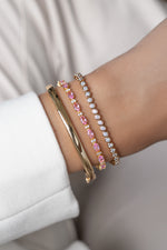Gold pink sapphire tennis bracelet stacked with bezel diamond bracelet and bangle.